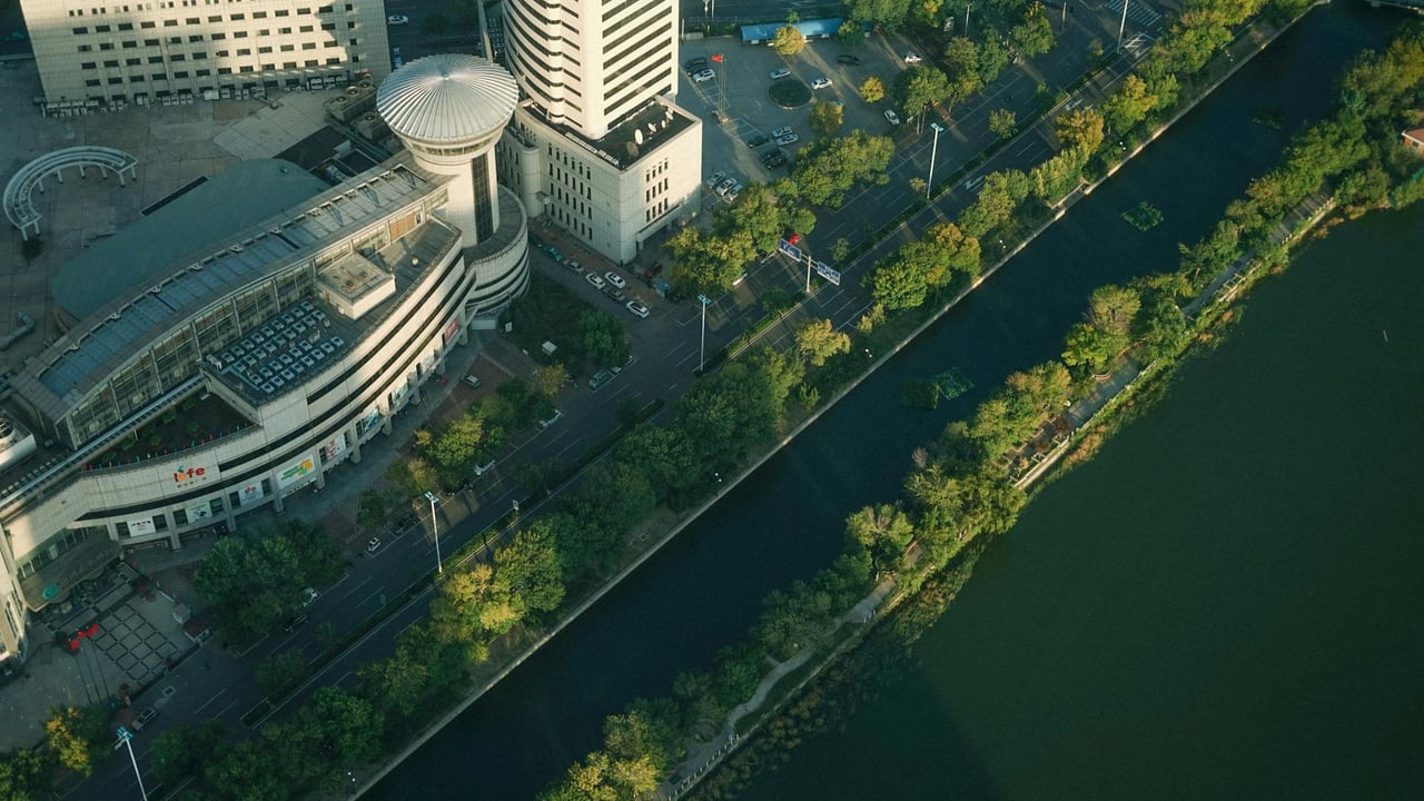 Aerial view of a modern cityscape with buildings and a canal flanked by greenery.