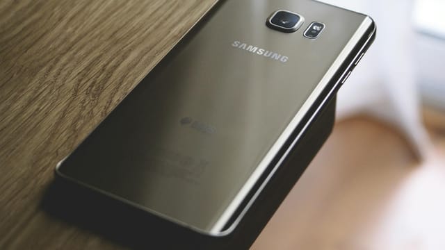 A sleek Samsung smartphone placed on a wooden surface, capturing modern elegance.