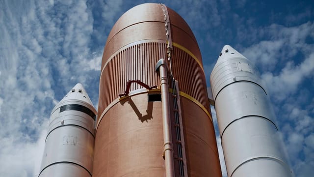 Dramatic view of rocket boosters against a bright blue sky, showcasing aerospace technology.
