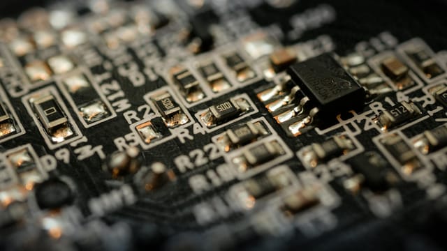 Detailed close-up of a microchip on an electronic circuit board with components and connections.