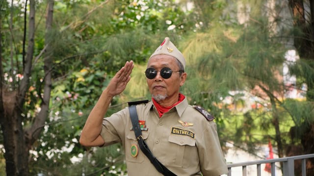 Portrait of Indonesian veteran saluting in Jakarta park.