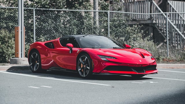 Red Ferrari SF90 Stradale sports car parked outdoors, showcasing sleek design and elegance.