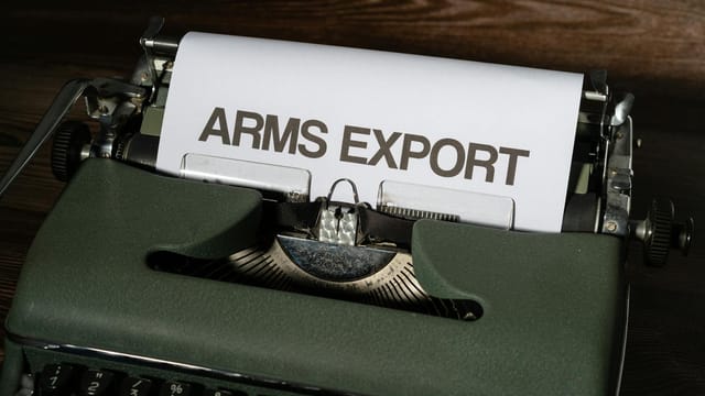 Close-up of a vintage typewriter with paper showing the text 'ARMS EXPORT'.