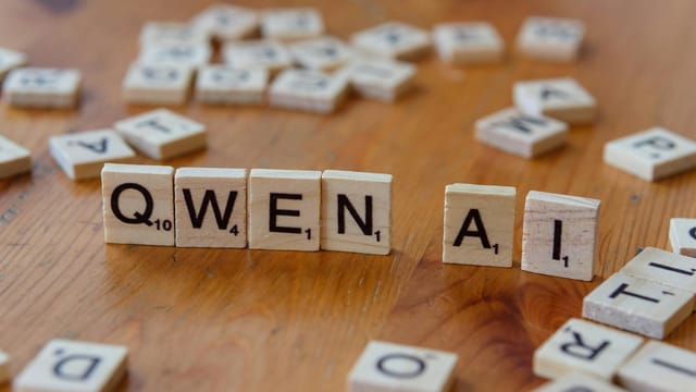 Scrabble-like tiles arranged to spell 'Qwen AI' on a wooden surface, depicting technology concepts.