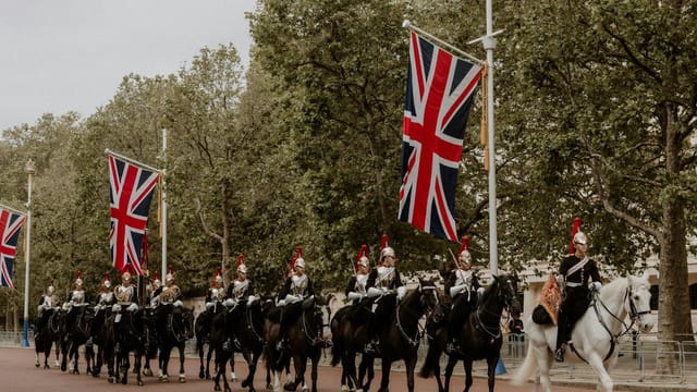 Ceremonial cavalry with Union Flags in a historical parade on The Mall, London.