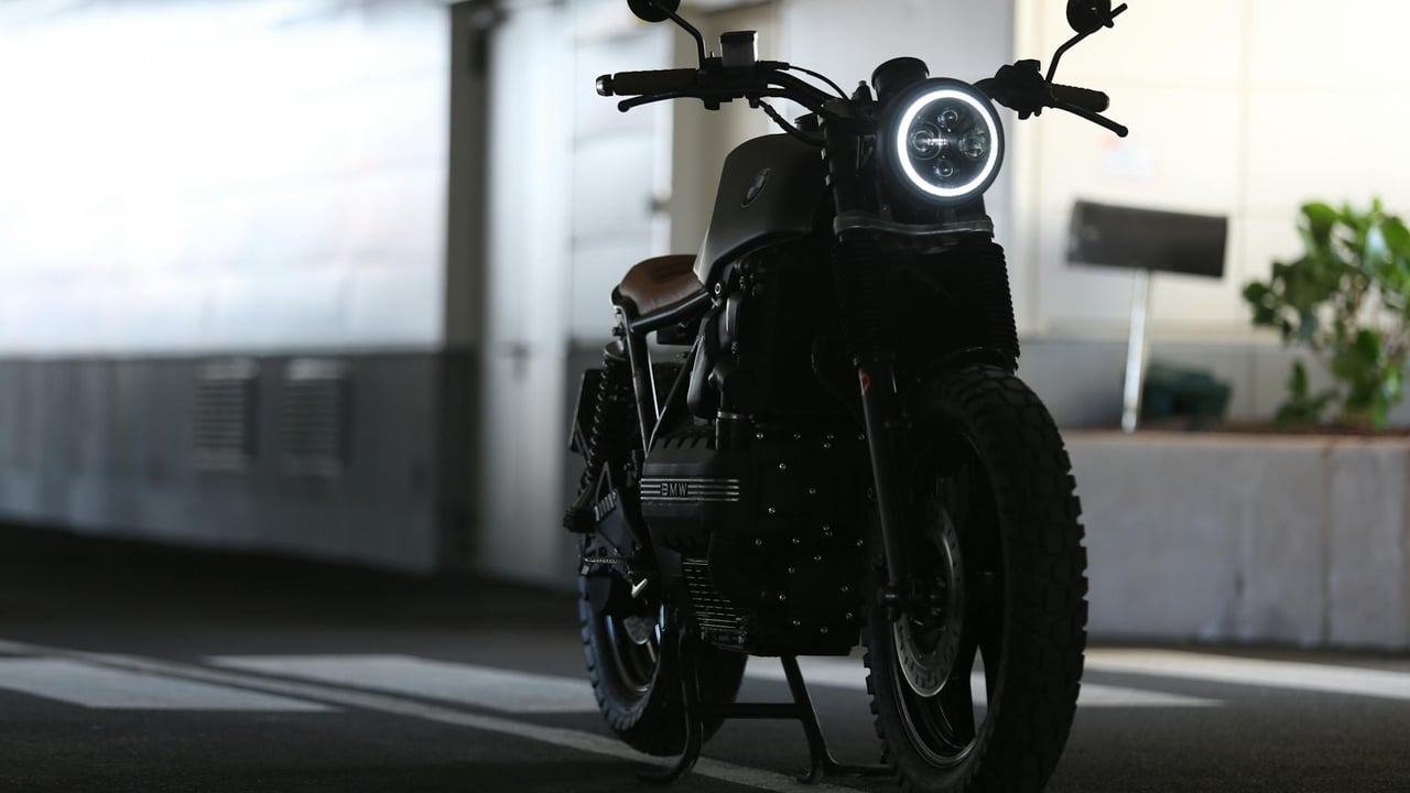 A sleek cafe racer motorcycle parked indoors with strong lighting contrast.