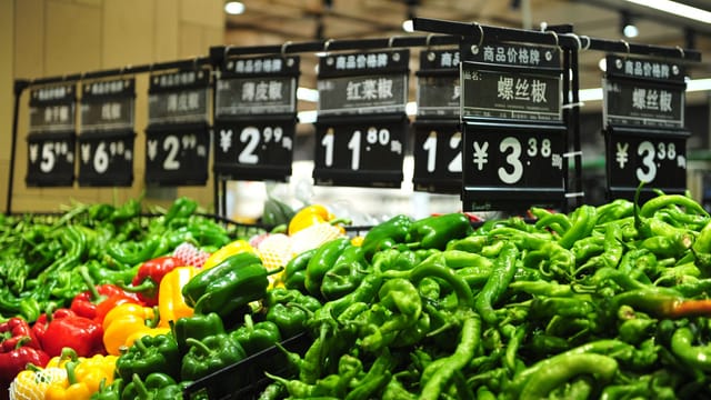 Vibrant bell peppers on display in a Chinese market with price tags.