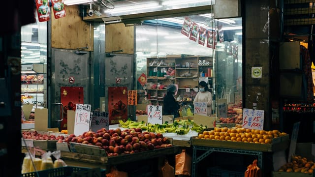 Vibrant Asian market scene featuring fresh produce, fruits, and daily shopper interactions.