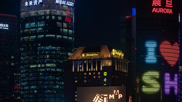 Vibrant Shanghai cityscape with skyscrapers lit up in neon at night.