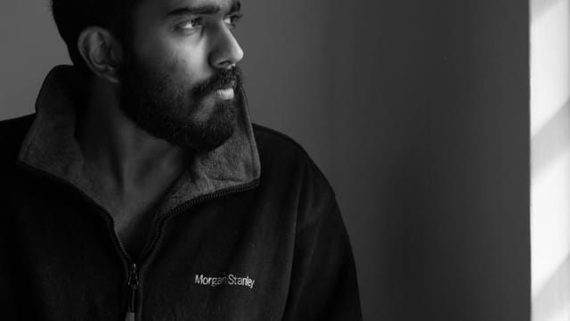 Artistic black and white portrait of a man looking thoughtfully out a window.