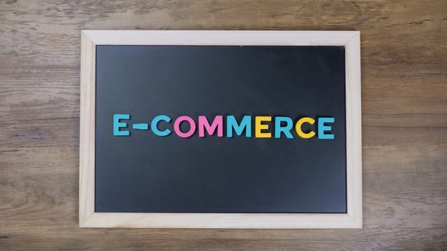 Colorful letters spelling 'e-commerce' on a wooden framed blackboard.