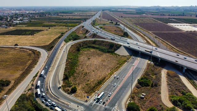 Aerial view capturing a busy highway intersection surrounded by agricultural fields and open landscape.