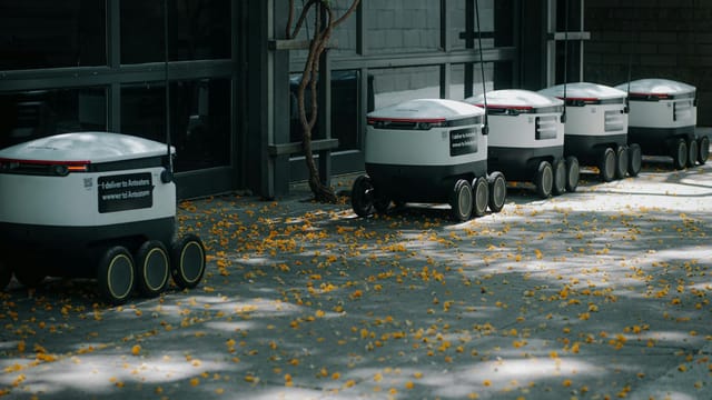 Autonomous delivery robots lined up outdoors showcasing modern transportation technology innovations.