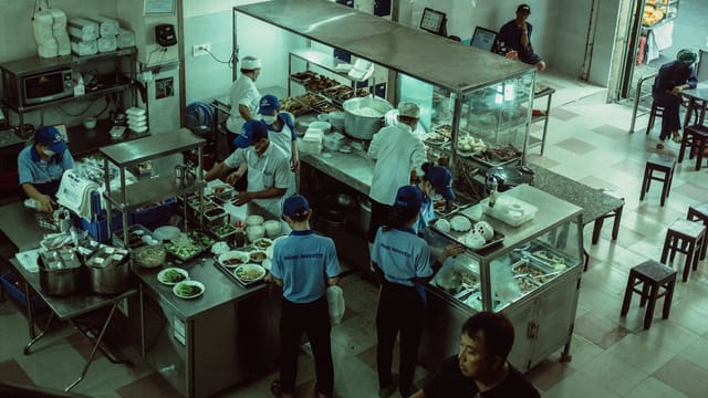Chefs preparing meals in a local eatery kitchen, seen from above.