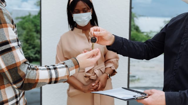 A real estate deal closure with masks during the COVID-19 pandemic, highlighting safety.