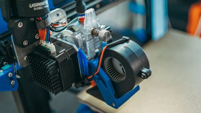 Detailed view of 3D printer parts showing wires and equipment in a workshop setting.