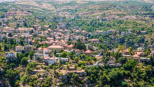 Breathtaking aerial view of a quaint village nestled in lush mountain terrain, showcasing stunning architecture.