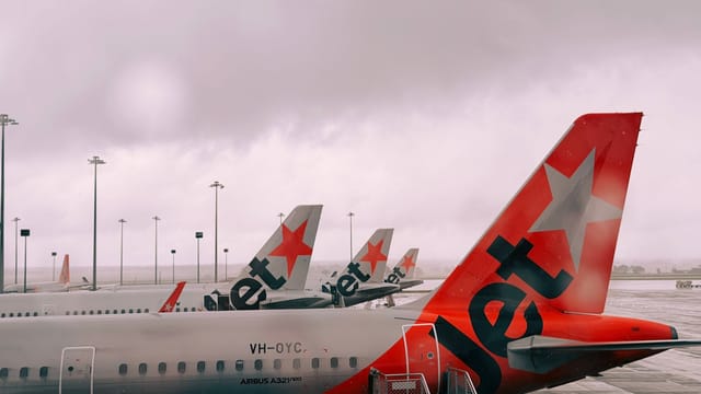 Jetstar Airbus A321neo airplanes lined at Melbourne Airport under a cloudy sky.