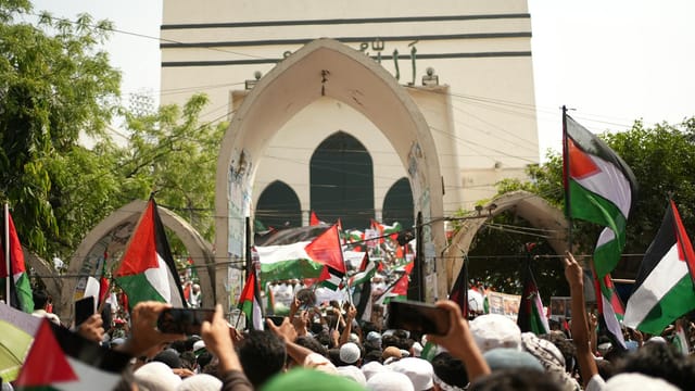 A large pro-Palestinian protest in Dhaka, Bangladesh with flags and banners.
