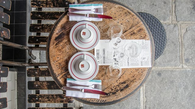 Top view of a vintage cafe table setting in Paris with wooden chairs and elegant tableware.