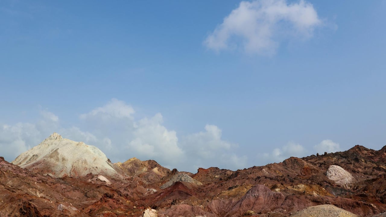 Discover the vibrant hills of Hormuz Island, Iran, under a bright blue sky.