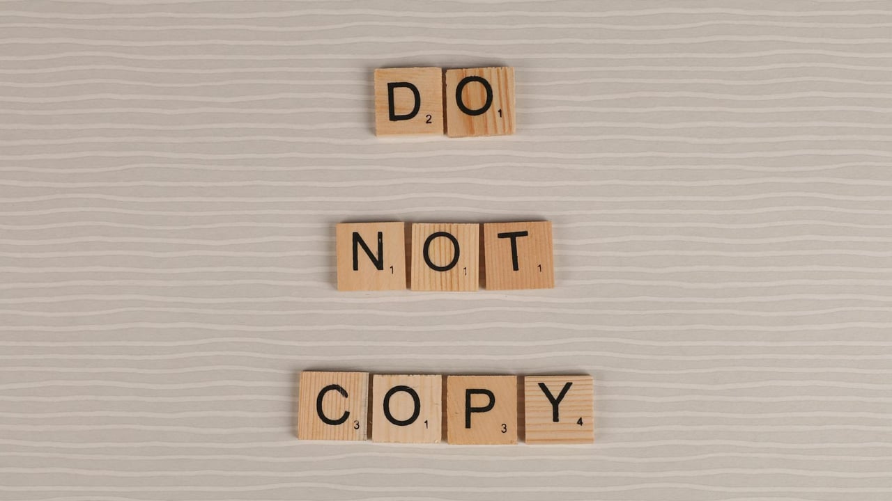 Close-up of wooden tiles spelling 'Do Not Copy' on a textured surface.