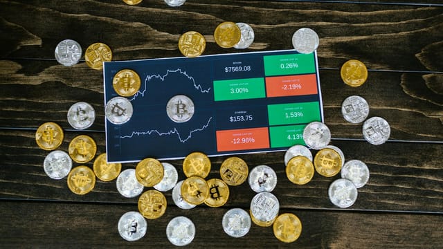 Bitcoin coins scattered around a stock chart on a dark wooden table, symbolizing cryptocurrency investment.