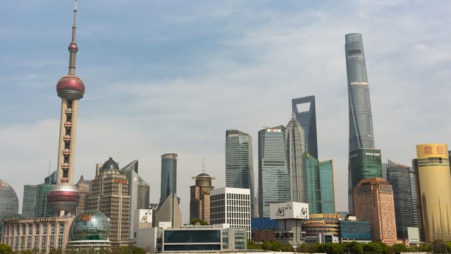 Panoramic view of Shanghai skyline featuring the Oriental Pearl Tower under a clear blue sky.