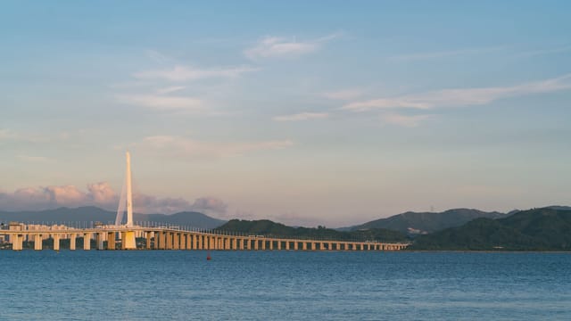 Tranquil scene of Shenzhen Bay Bridge against a serene sunset backdrop over calm waters.