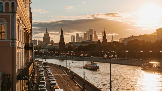 Golden sunset over Moscow's river with the Kremlin and skyscrapers in view.