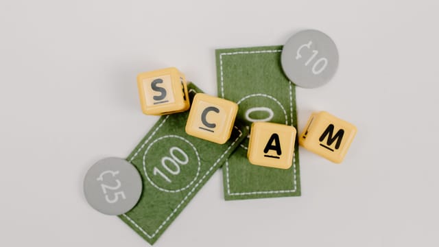 Yellow dice spelling 'Scam' on fake currency, representing financial deception.