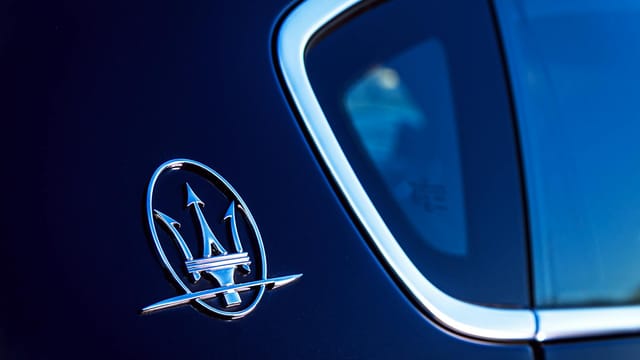Elegant close-up of the iconic Maserati logo on a luxury vehicle, exuding style and sophistication.