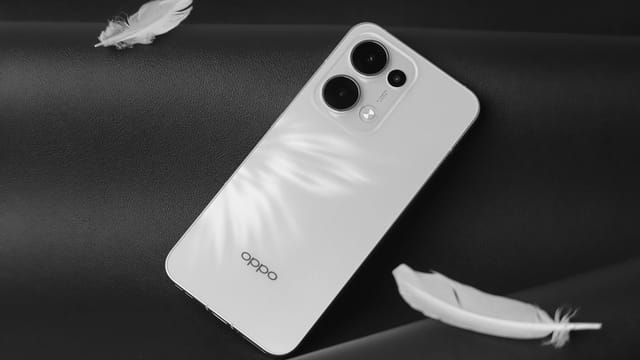 Minimalist white smartphone with feathers on a black surface, creating a modern and sleek aesthetic.