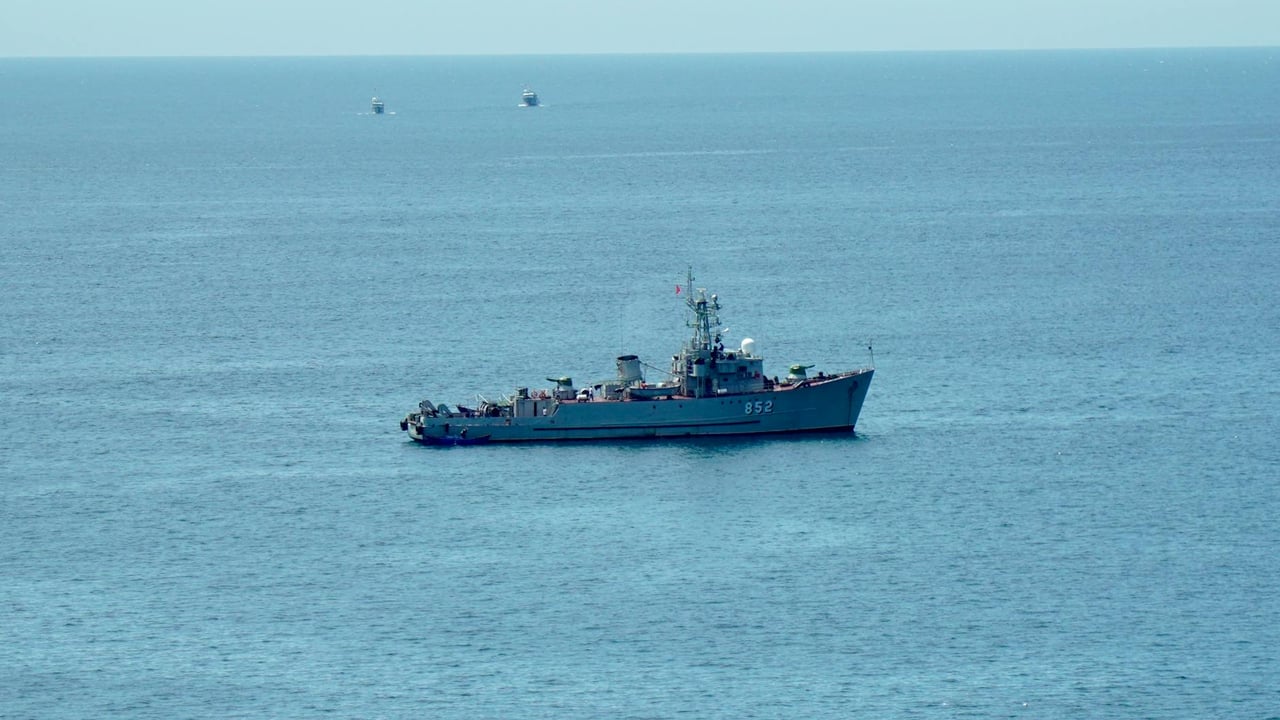 A military ship navigating the calm blue ocean under a clear sky, showcasing nautical power.