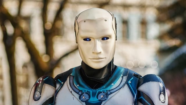Close-up of a humanoid robot with a futuristic design posing outdoors.
