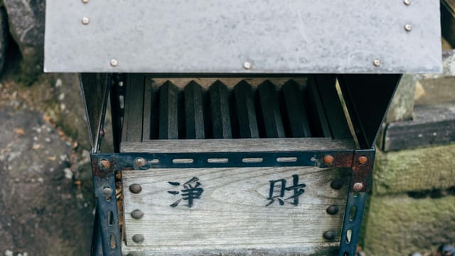 Close-up of a traditional Japanese shrine donation box with kanji characters.