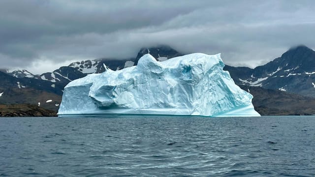 Expansive iceberg floating serenely in the cool waters of Greenland.