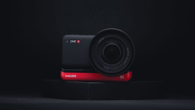 Close-up of Insta360 One R action camera on dark surface, highlighting its sleek design.