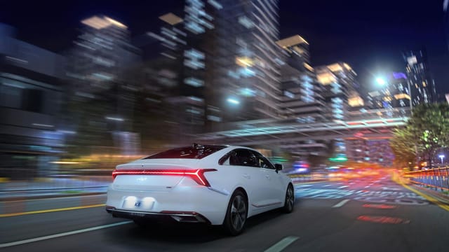 White sedan speeding through a vibrant, neon-lit city street at night capturing urban energy.