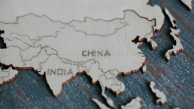 Detailed view of Asia carved on a wooden map, highlighting China and India.
