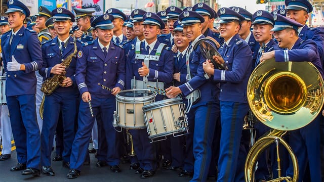 A lively military band in uniform performing outdoors in Taiwan street parade.