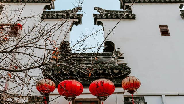 A view of traditional Chinese architecture with red lanterns in Nanjing during autumn.