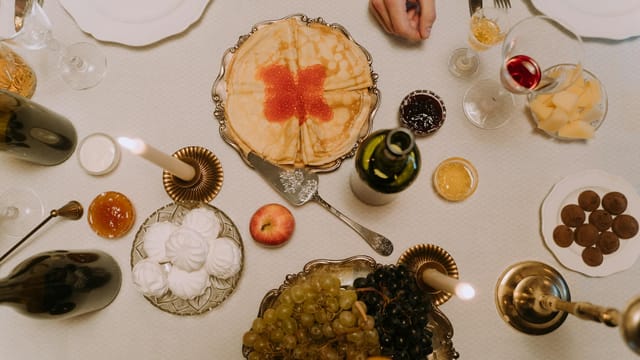 A lavish table setting featuring pancakes, wine, fruits, and various delicacies for a fine dining experience.