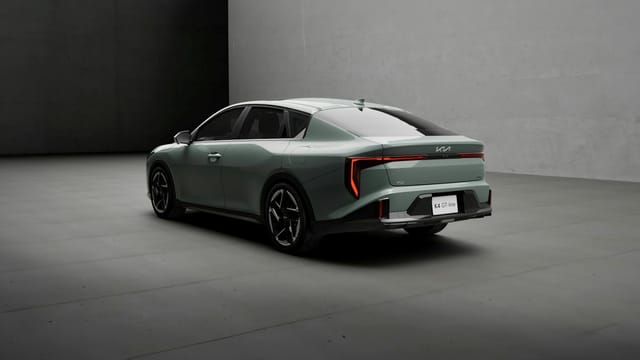 A modern gray Kia K4 GT Line vehicle in a minimalist indoor environment.