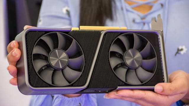 Detailed shot of hands holding a modern graphics card indoors.