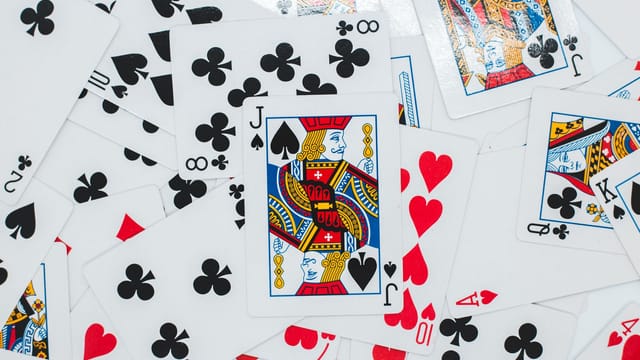 Overhead view of backdrop representing various playing cards with bright suit symbols and illustrations with glowing surface
