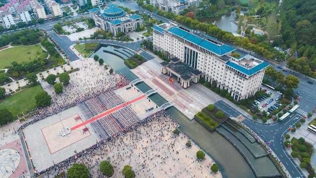Aerial view capturing a busy city square filled with people and surrounded by buildings in China.