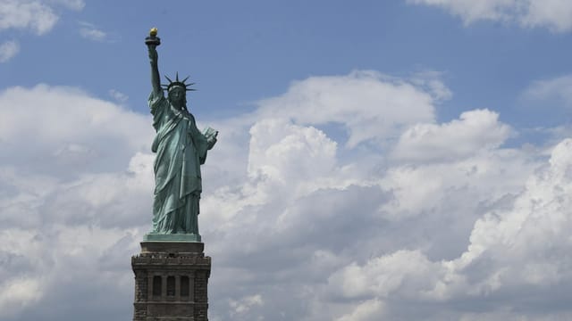View of the iconic Statue of Liberty with a vibrant blue sky background, symbolizing freedom.