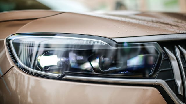 Detailed close-up of a modern car's headlight, showcasing sleek design and glossy finish.
