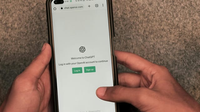 Close-up of hands using smartphone with ChatGPT app open on screen.